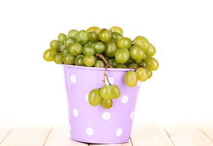 在白色背景上的木桌上的桶中成熟绿葡萄