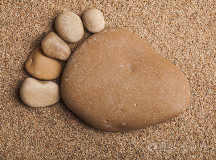 单独跟踪足迹脚的石头做成的卵石海砂纹理背景上