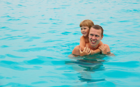 快乐的孩子和父亲在热带度假村在海中游泳