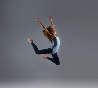 年轻 有吸引力 运动和的现代舞蹈家，跳过灰色背景