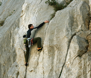 宽河谷的背景上用石灰石墙上爬的年轻男子