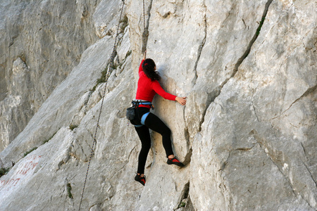 宽河谷的背景上用石灰石墙上爬的年轻女子