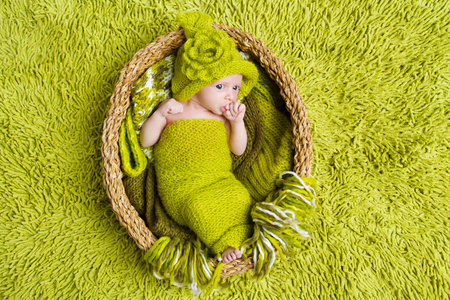 在绿色背景的羊毛帽子初生婴孩