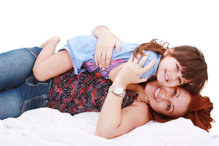 快乐年轻的母亲和她的女儿在家里的床上玩