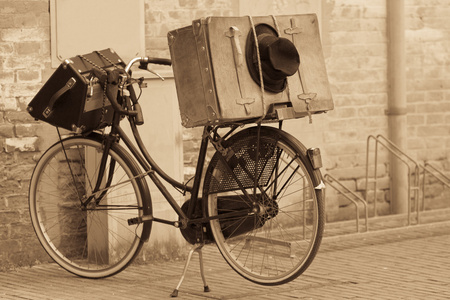 破旧的黑帽子和行李箱上的自行车照片