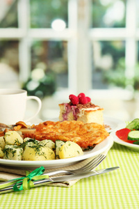 烤鸡排煮的土豆和黄瓜，杯茶和甜点在咖啡馆室内绿色表布上