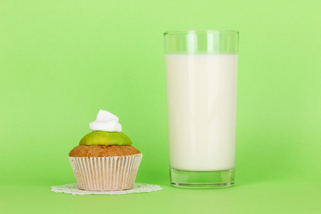 一杯新鲜新牛奶与绿色背景上蛋糕