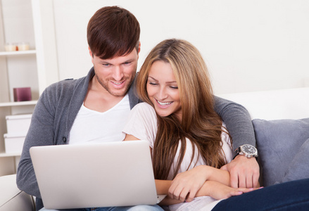 快乐年轻夫妇在家中使用计算机