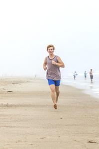 在空的海滩在早上可爱年轻十几岁的男孩 joging