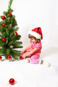 小女孩坐在新的一年或圣诞树上孤立附近
