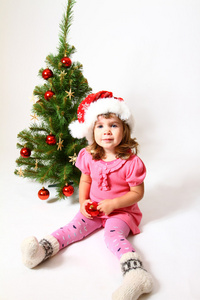 孩子戴着帽子的圣诞老人 一个红球和一棵圣诞树