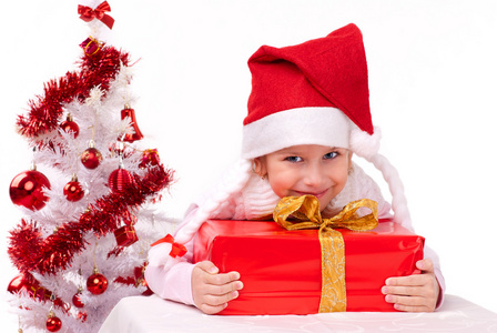 快乐的小女孩与附近一个白色的人造圣诞树圣诞礼物