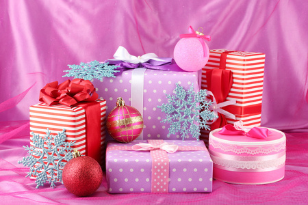 多彩的紫色 红色和粉色礼品圣诞球与粉红色的背景上的雪花