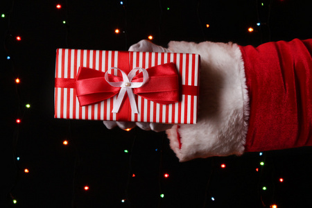 圣诞老人只手握住在明亮的背景上的礼品盒