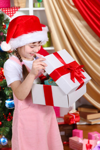一个小女孩在欢乐地装饰的屋子中打开一份礼物
