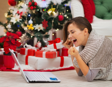 笔记本电脑附近的圣诞树欣喜成功的幸福女人