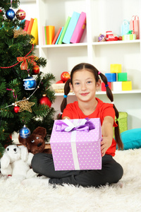 持有礼品盒圣诞节树附近的小女孩