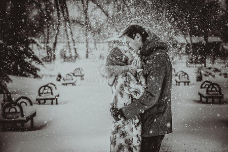 年轻夫妇在雪上亲吻。黑白相间。