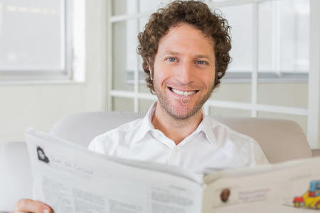 微笑的男人在家看报纸