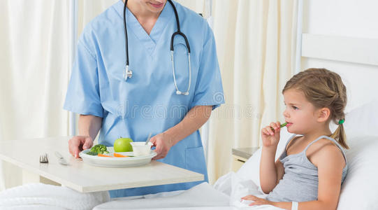 医生给生病的女孩喂早餐