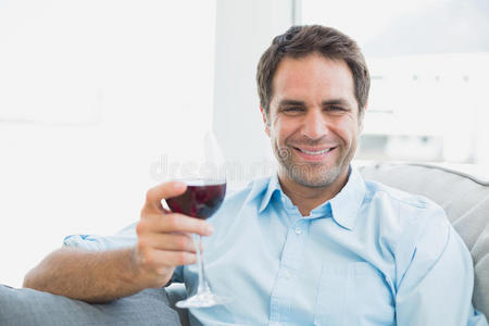 坐在沙发上喝着红酒的快乐男人