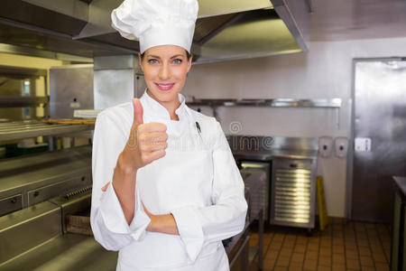 微笑的女厨师在厨房里竖起大拇指