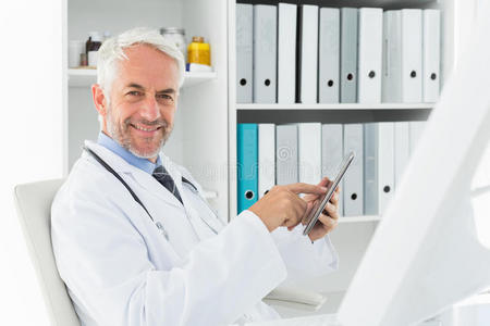 微笑男医生在医务室使用数码平板电脑