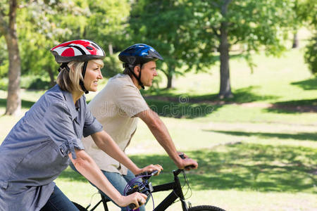 一对快乐的情侣在公园里骑车图片