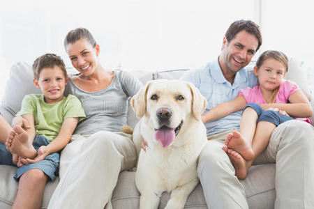 快乐的一家人和他们的宠物拉布拉多坐在沙发上