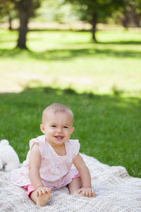 可爱的宝宝坐在公园的毯子上图片