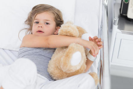 病床上拥抱泰迪熊的可爱女孩
