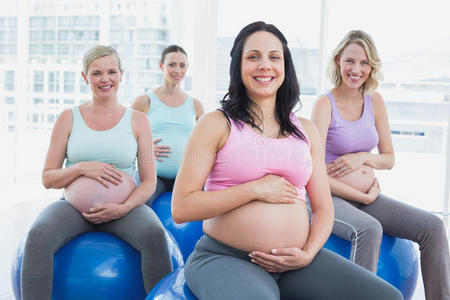 坐在健身球上微笑的孕妇
