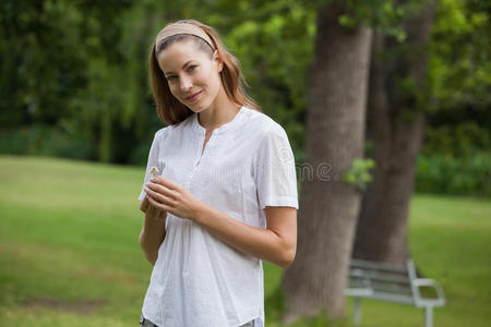 微笑的年轻女子拿着一朵花在公园里