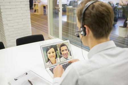 商务人士在办公室用耳机skype进行视频会议