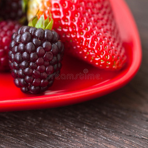 多汁的草莓和黑莓在一个木制的盘子里