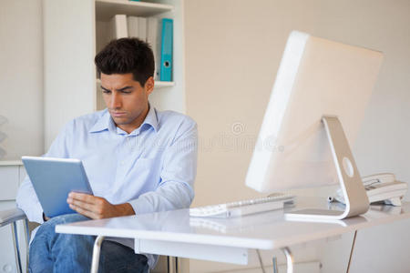随便的商人在办公桌上用他的平板电脑