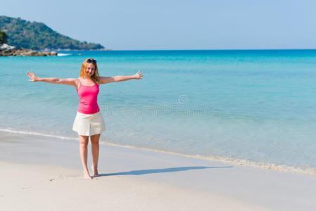 穿着上衣和米色裙子的女人在沙滩上散步