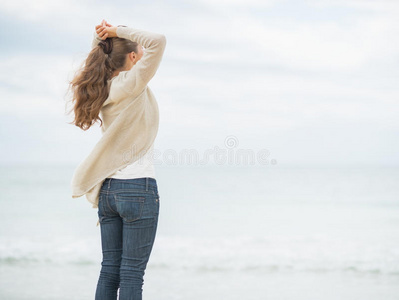 寒冷海滩上的年轻女子望着远方