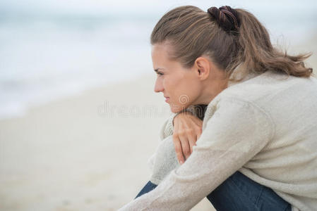 坐在冰冷的海滩上平静的年轻女子