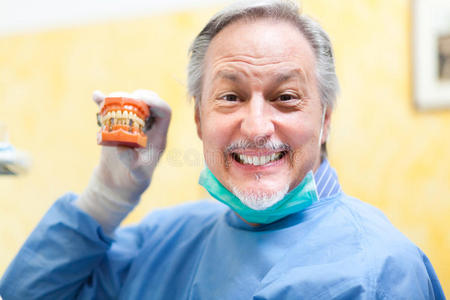 微笑的牙医拿着假牙