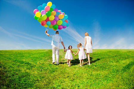 幸福的一家人在户外举着五颜六色的气球。妈妈，德德和两个