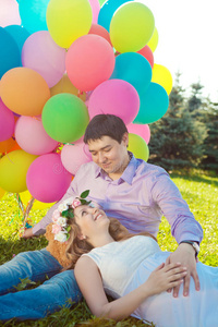年轻健康的美女孕妇带着丈夫和气球