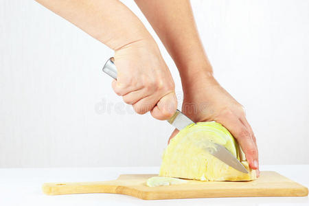 手拿刀把卷心菜切碎放在木制的切菜板上