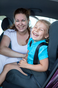 母亲带着小女儿在汽车后座上笑