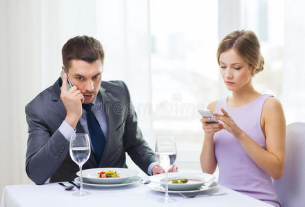 一对忙碌的夫妇在餐厅拿着智能手机