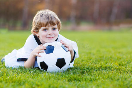 无辜的巴西四岁的金发男孩在足球场上踢足球照片