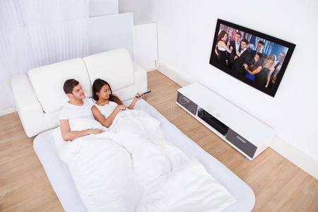 聚会看电视一对夫妇在家里躺在床上看电视照片