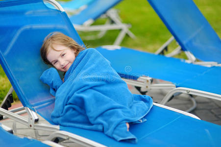 坐在游泳池附近的女孩裹着毛巾