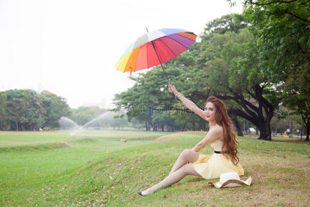 带着伞坐在草坪上的女人。
