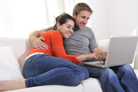 快乐夫妻在沙发上的笔记本电脑上享受网上购物的乐趣